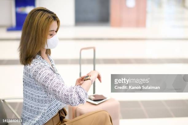 young woman with protective face mask checking the time and waiting at the airport - kündigungsfrist stock-fotos und bilder