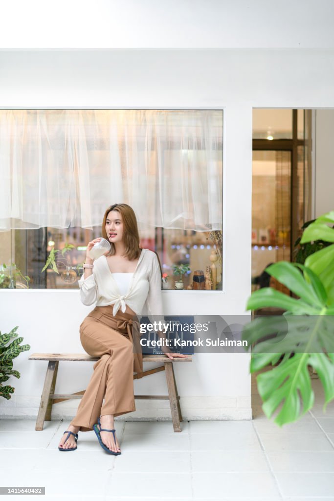 Asian woman sitting by the window drinking lemon lime soda
