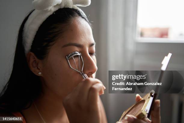 close up view of a young woman using an eyelash curler at home - curled up stock pictures, royalty-free photos & images