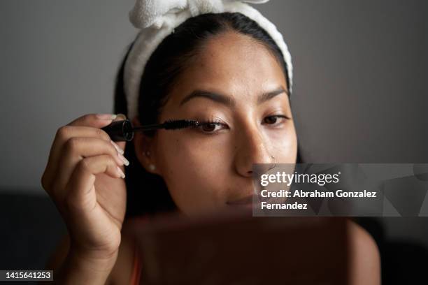young woman applying mascara at home - mascara stockfoto's en -beelden