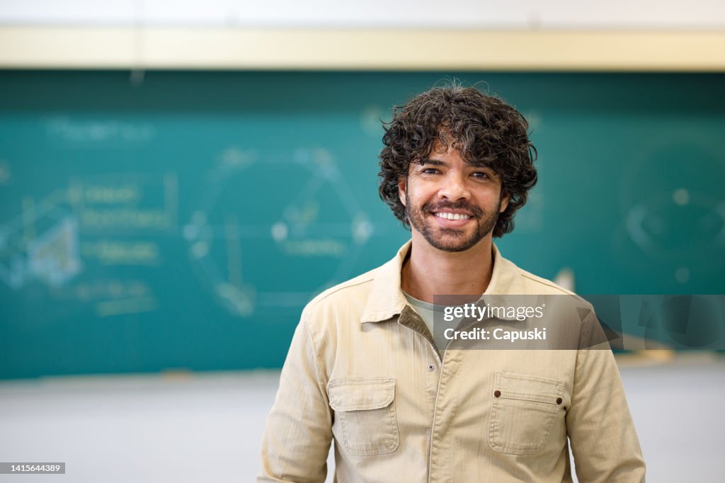 Professor sorrindo na frente do quadro-negro