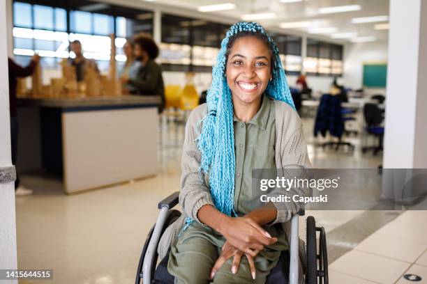 studente sorridente su una sedia a rotelle di fronte alla classe - sedia a rotelle foto e immagini stock
