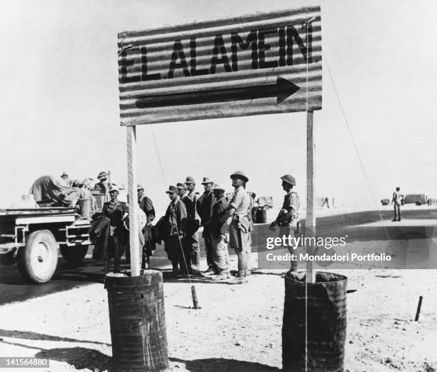 German prisoners of the Afrika Korps stopping next to a roadsign that shows the way to El Alamein, after the Battle of El Alamein, Egypt, October...