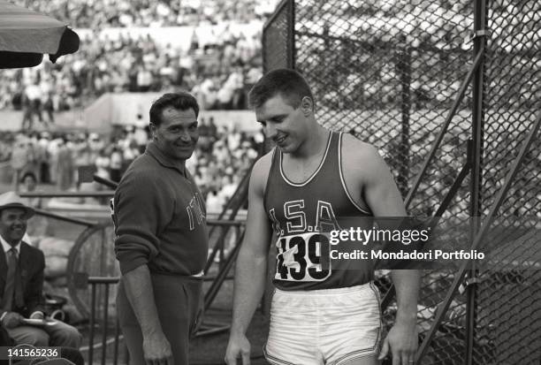 The American athlete Al Oerter partecipating at the throw of the discus competition.The Italian athlete Carmelo Rado is smiling at him. Rome, 1960