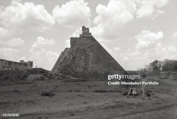 Two women dressed with modern Western clothes are walking near the remains of a huge Aztec temple, built when Mexico City was the ancient town...