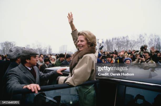 British Prime Minister Margaret Thatcher waves to a crowd of onlookers as she stands in the open door of a car during a State Visit to the Soviet...