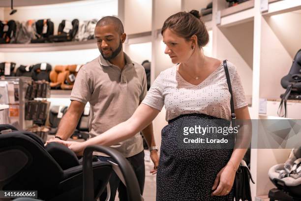 gemischtrassige schwangere paar, das babybedarf einkauft - babyausrüstung stock-fotos und bilder