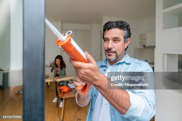 man at home grouting his balcony door - caulk stockfoto's en -beelden