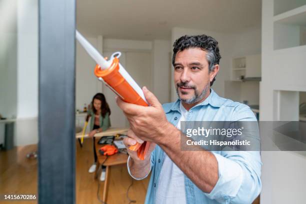 man at home grouting his balcony door - caulk stock pictures, royalty-free photos & images
