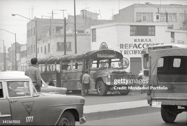 Mexican men looking at a bus burned during the clashes between the student movement and the army in Mexico City. Mexico City, October 1968