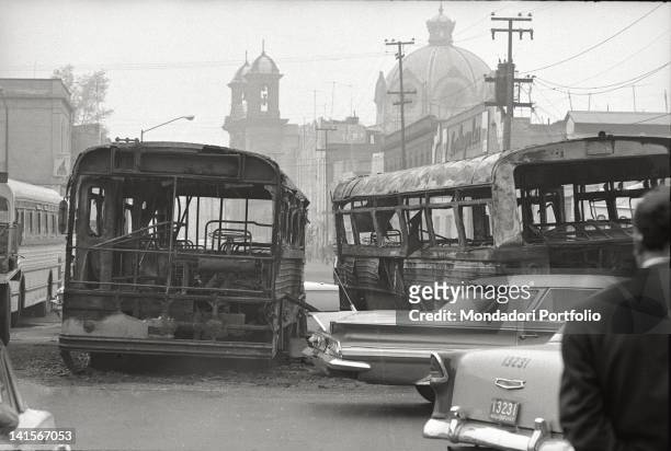 Mexican man looking at two buses burned during the clashes between the student movement and the army in Mexico City. Mexico City, October 1968