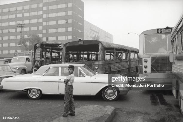 Mexican child looking at two buses burned during the clashes between the student movement and the army in Mexico City. Mexico City, October 1968