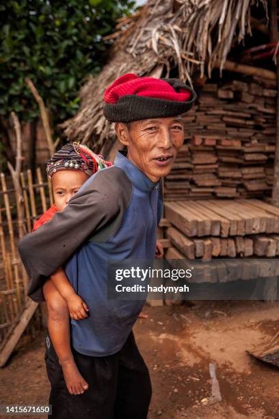 old man from the hill tribe carrying his granddaughter - laos stockfoto's en -beelden