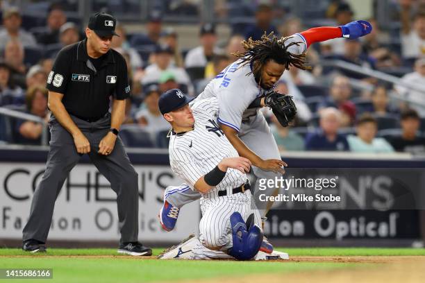 Vladimir Guerrero Jr. #27 of the Toronto Blue Jays slides in safely on Lourdes Gurriel Jr. #13 single to right field ahead of the tag by Josh...