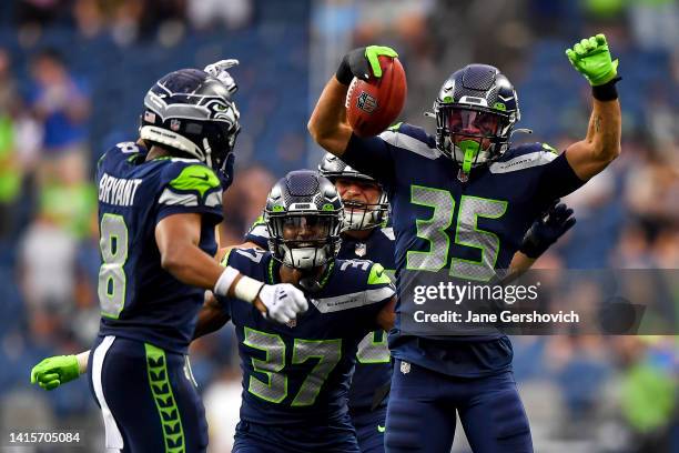 Joey Blount celebrates with Coby Bryant and Elijah Jones of the Seattle Seahawks after recovering an onside kick in the fourth quarter during the...