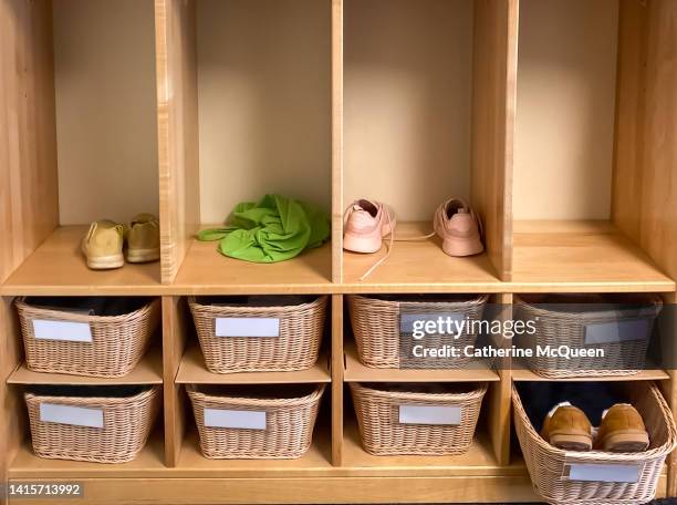 wicker basket storage cubbies & closets in preschool classroom with various belongings in view - shoes closet ストックフォトと画像