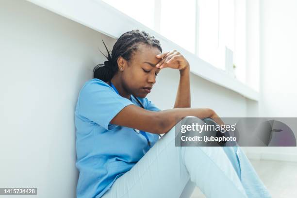 tired nurse sits on floor in the lobby of medicine clinic after a hard dutty - sad nurse stock pictures, royalty-free photos & images