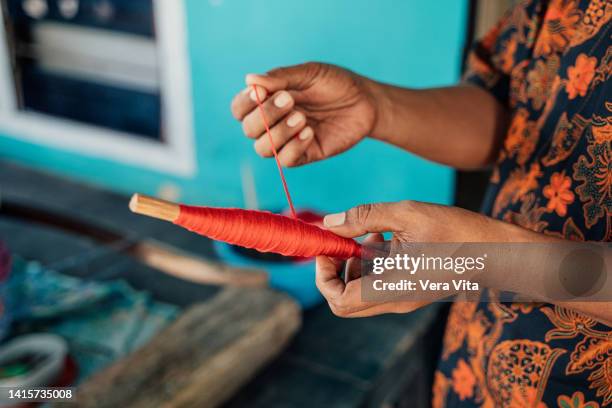 asian woman hands holding reel of red threat in indonesia. - mani fili foto e immagini stock
