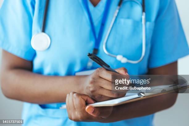 unrecognizable nurse checking a patients medical chart - medical chart stock pictures, royalty-free photos & images