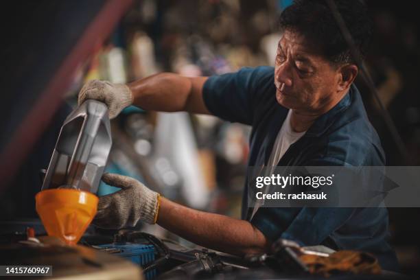 un hombre vertiendo aceite al motor en el taller de reparación de automóviles. - oil change fotografías e imágenes de stock