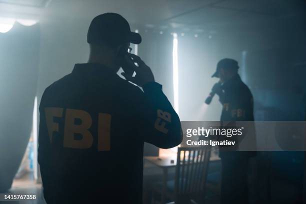 scena di un film d'azione con due agenti dell'fbi sulla scena del crimine in una stanza appannata dell'appartamento del criminale, che chiamano i criminologi - fbi agents foto e immagini stock