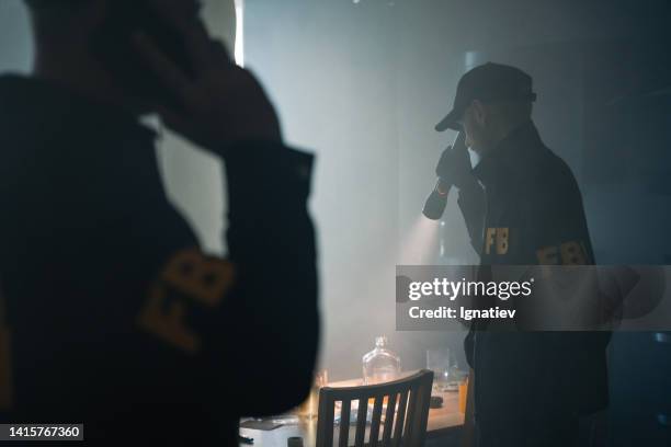 two fbi agents with a flashlight at the crime scene in a foggy room - police scrutiny stock pictures, royalty-free photos & images