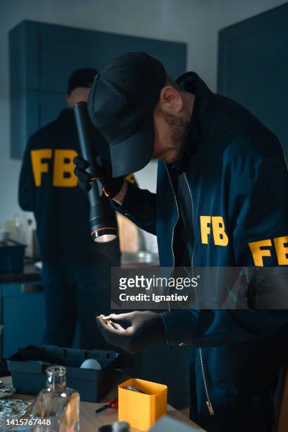 fbi agents, examining physical evidences with a flashlight at the crime scene, probably at the den of criminals - fbi warning stock pictures, royalty-free photos & images