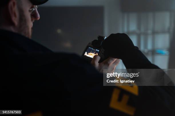 an fbi agent looks into the camera with the photos he took for the case, we see the camera screen from over his shoulder - police scrutiny stock pictures, royalty-free photos & images