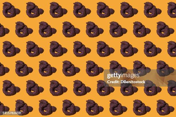 pattern of human or animal poops of brown color, lying, on a yellow background. concept of defecate, poop, shit and prank. - coco brown imagens e fotografias de stock