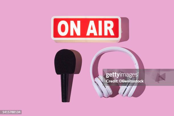 lightbox turned on with the word 'on air', headphones and microphone with windscreen on pink background. concept of radio, podcast, streaming, broadcast, journalism, reporting and shows. - on air sign imagens e fotografias de stock