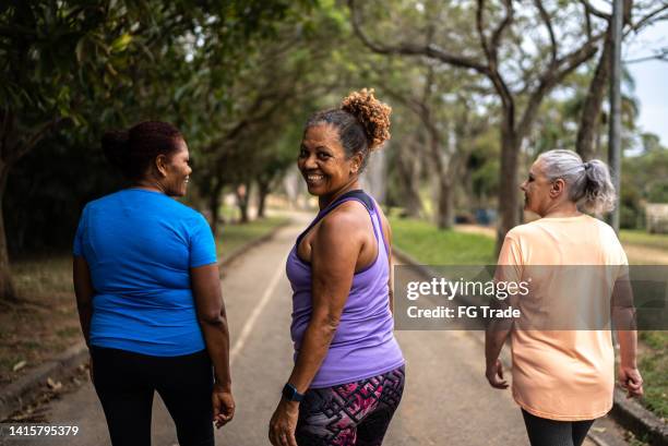 portrait of a senior woman walking in the park with friends - walking stock pictures, royalty-free photos & images