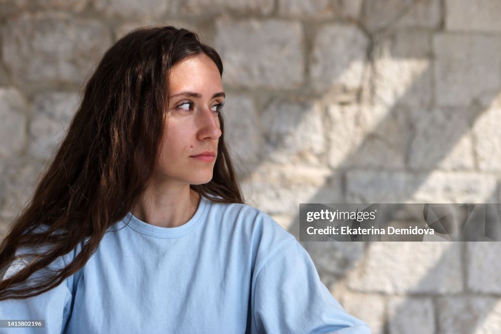 Uncertain woman looking away suspiciously against brick wall