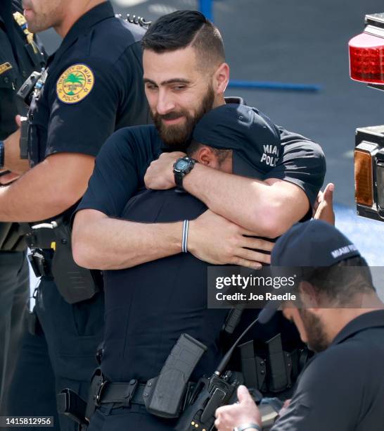 Police officers hug as they attend the honor procession for Miami-Dade Detective Cesar Echaverry who was killed in the line of duty on August 19,...