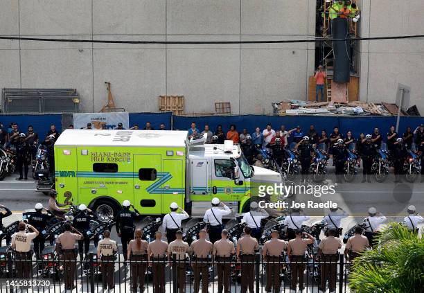 Police officers salute as a Miami-Dade Fire Rescue truck carries the casket of Miami-Dade Detective Cesar Echaverry during a honor procession to the...