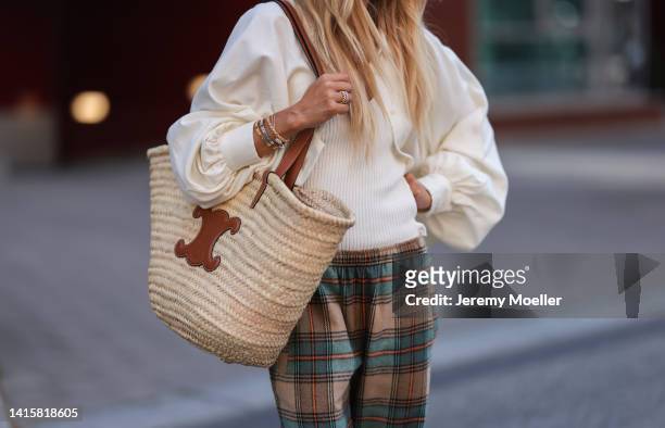 Sue Giers is seen wearing SoSue brown, blue, beige and red checked pattern pants, a white blouse and SoSue top, brown Birkenstock shoes and a vintage...