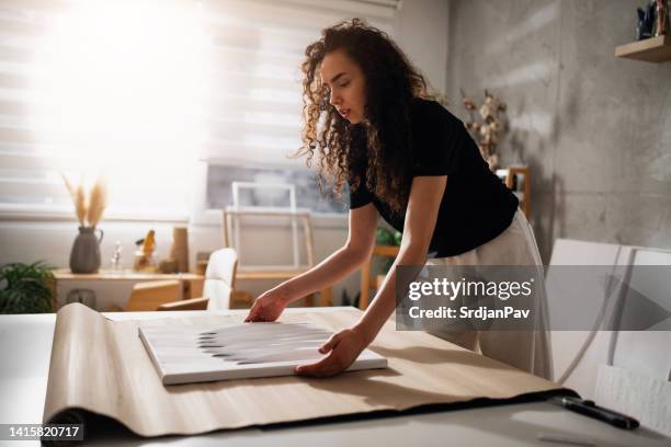 young woman, an artist and online seller, packaging a painting for shipping - textile for delivery stock pictures, royalty-free photos & images