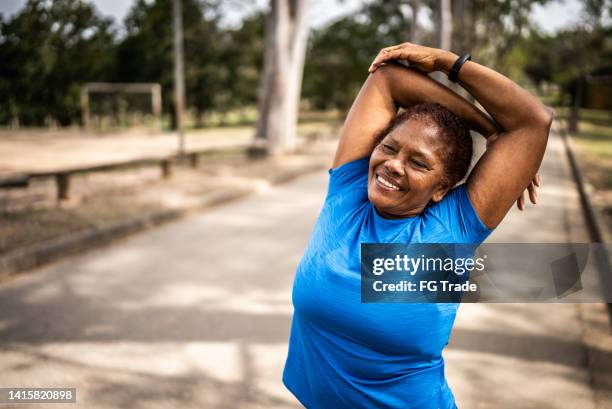 senior woman stretching in a park - women stretching stock pictures, royalty-free photos & images