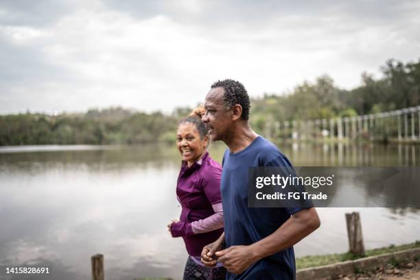 senior couple jogging in a park - interracial wife photos stock pictures, royalty-free photos & images