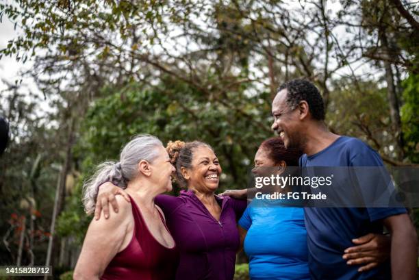 happy senior friends embracing in a park - senior men group stock pictures, royalty-free photos & images