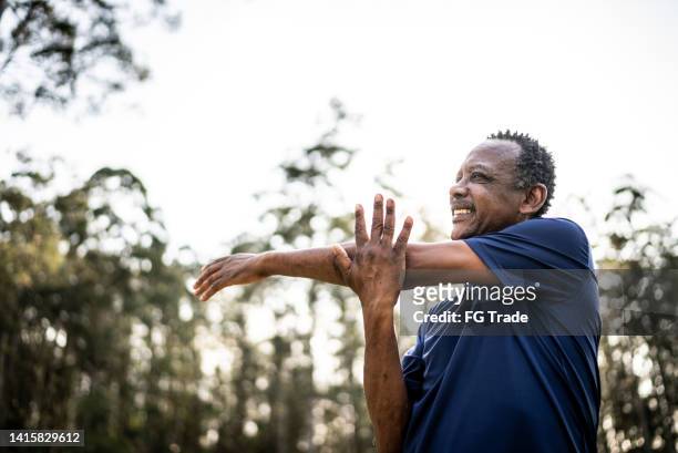senior man stretching in a park - arm pit stockfoto's en -beelden