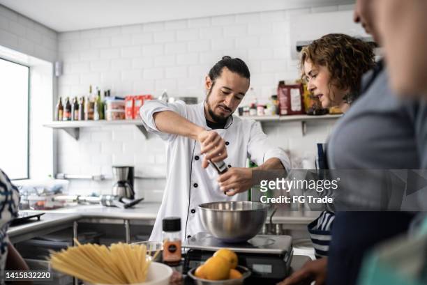 chef giving instructions to adult students in a cooking class - pepper pot stock pictures, royalty-free photos & images