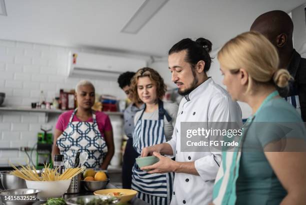 koch gibt den schülern im kochkurs anweisungen - cookery class stock-fotos und bilder