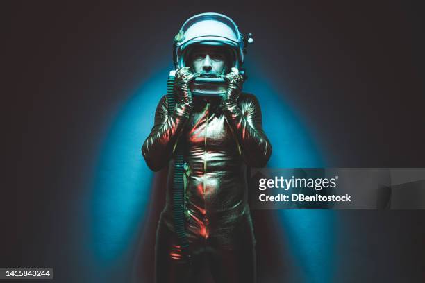 astronaut cosmonaut dressed in a gold jumpsuit and helmet, illuminated by blue and red lights, looking at camera, in verse mood. concept of exploration, space, planet, strange and alien. - captain planet 個照片及圖片檔