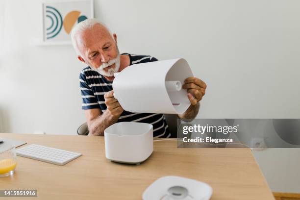 idoso em uma nova casa que monta umidificador - humidifier - fotografias e filmes do acervo