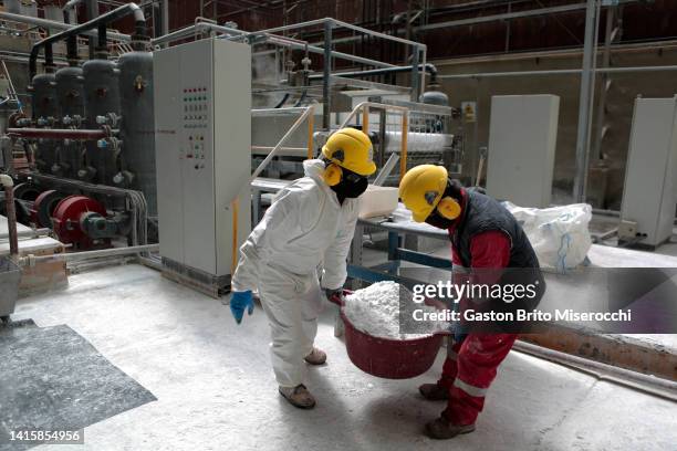 Two workers hold a bucket with lithium carbonate at the Llipi pilot Plant in the Uyuni Salt Flats on August 14, 2022 in Uyuni, Bolivia. The Uyuni...