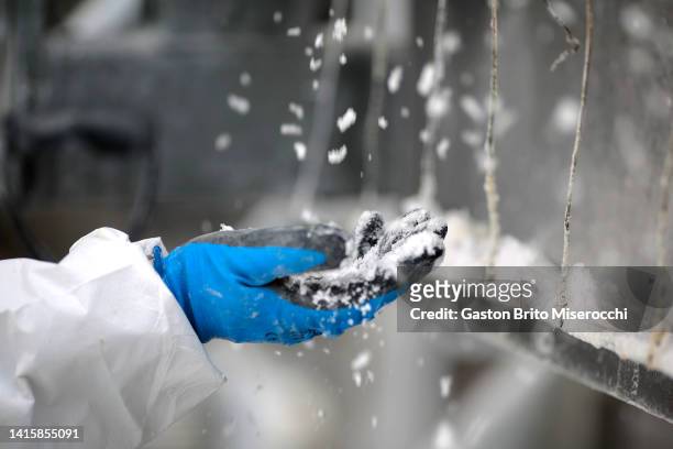 Worker using gloves touches the lithium carbonate in the belt filter press at the Llipi pilot Plant in the Uyuni Salt Flats on August 14, 2022 in...