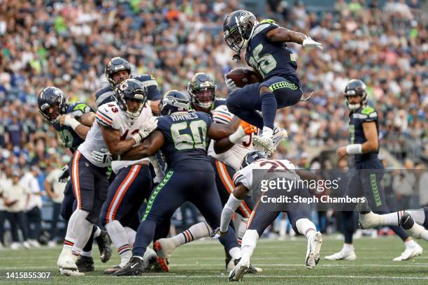 Darwin Thompson of the Seattle Seahawks leaps over Darrynton Evans of the Chicago Bears in the third quarter during the preseason game at Lumen Field...