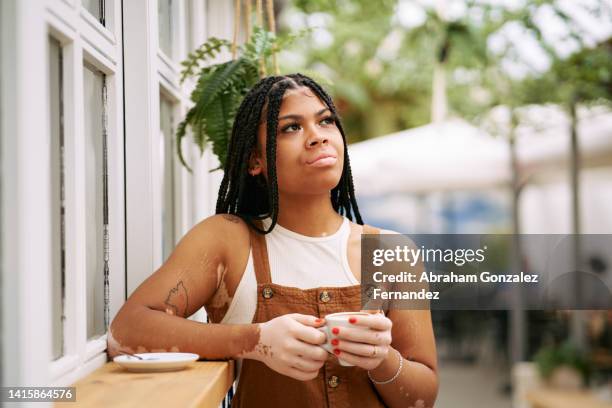 a young woman with vitiligo drinking coffee in an outdoor cafe standing up. - leaning on elbows stock pictures, royalty-free photos & images