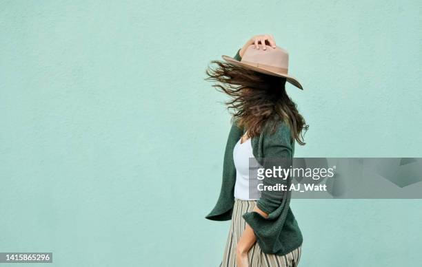 side view of a young woman holding her hat in breeze - mint green stock pictures, royalty-free photos & images