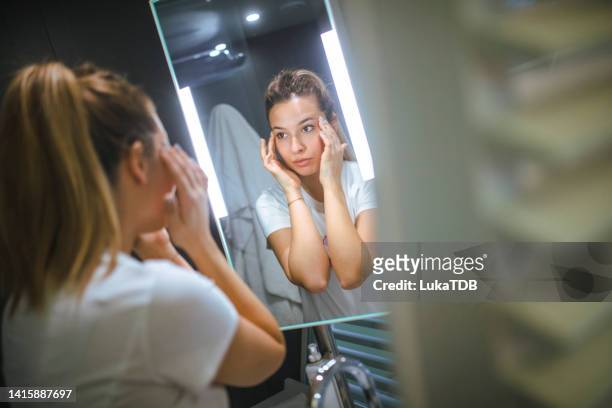 the woman looks in the mirror after applying face cream. - night at the net stockfoto's en -beelden